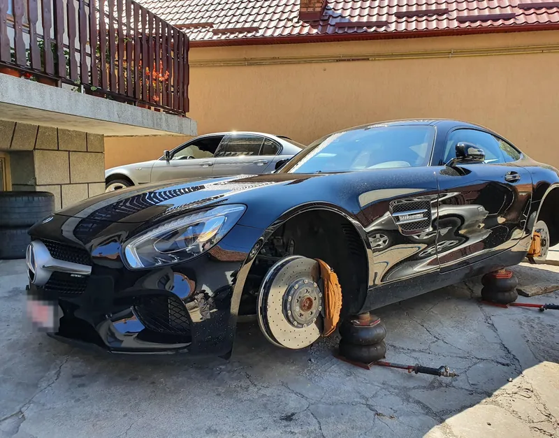 Mercedes-AMG GT negru ridicat pe perne, cu roțile demontate