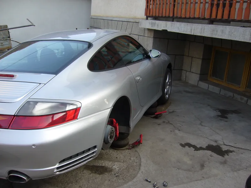 Porsche 911 argintiu, văzut din spate, cu roata din spate demontată