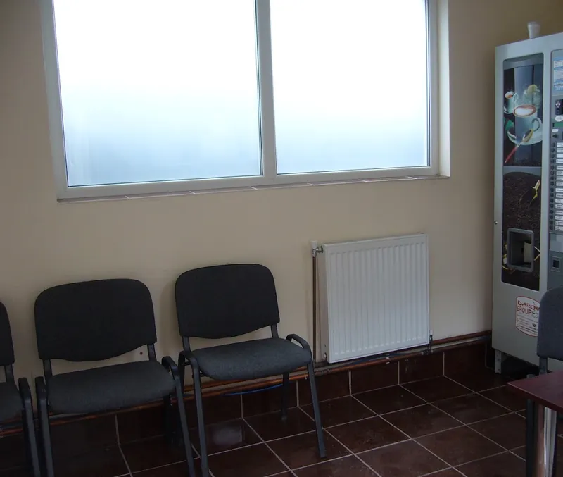 Sala de așteptare a atelierului: scaune, calorifer și automat de cafea