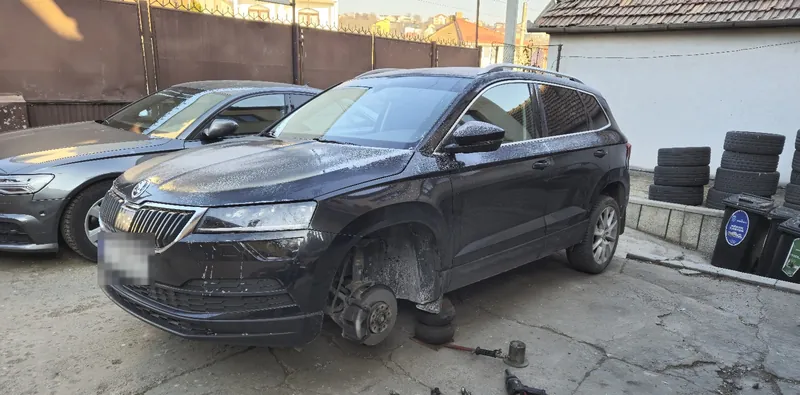 Skoda Karoq negru cu roata din față demontată, în curtea atelierului